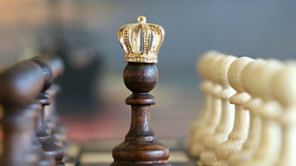 Chess pieces. Dark pawn wears a gold crown.